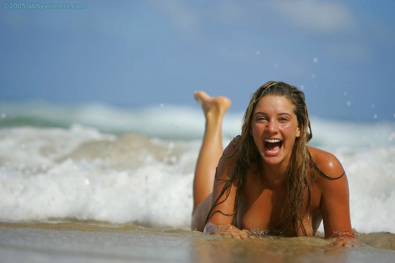 Обнаженная девушка на пляже дурачится и мило позирует