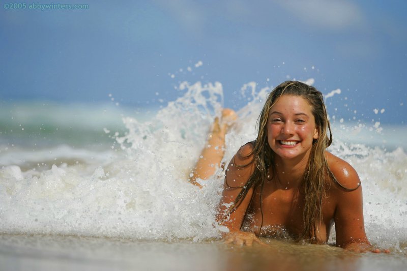 Обнаженная девушка на пляже дурачится и мило позирует